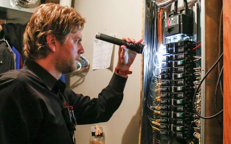 Lars Knobloch doing a thorough home inspection with a flashlight