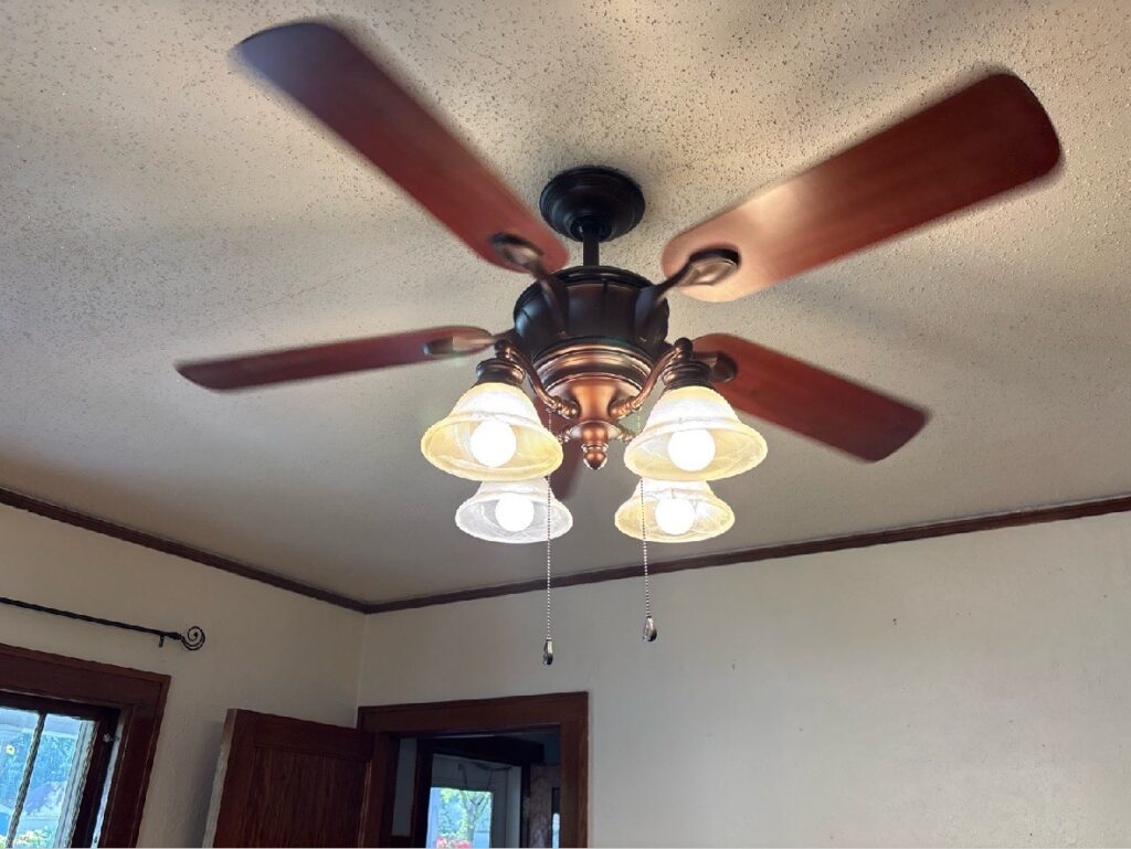 Bronze five-blade ceiling fan with wood blades and a four-light glass kit.