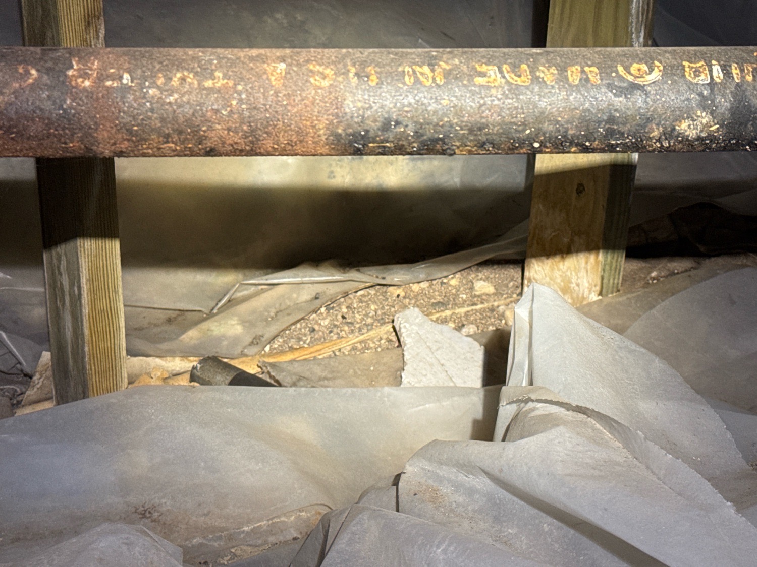 Loose, bunched plastic sheeting on a crawl space floor that is not lapped or sealed