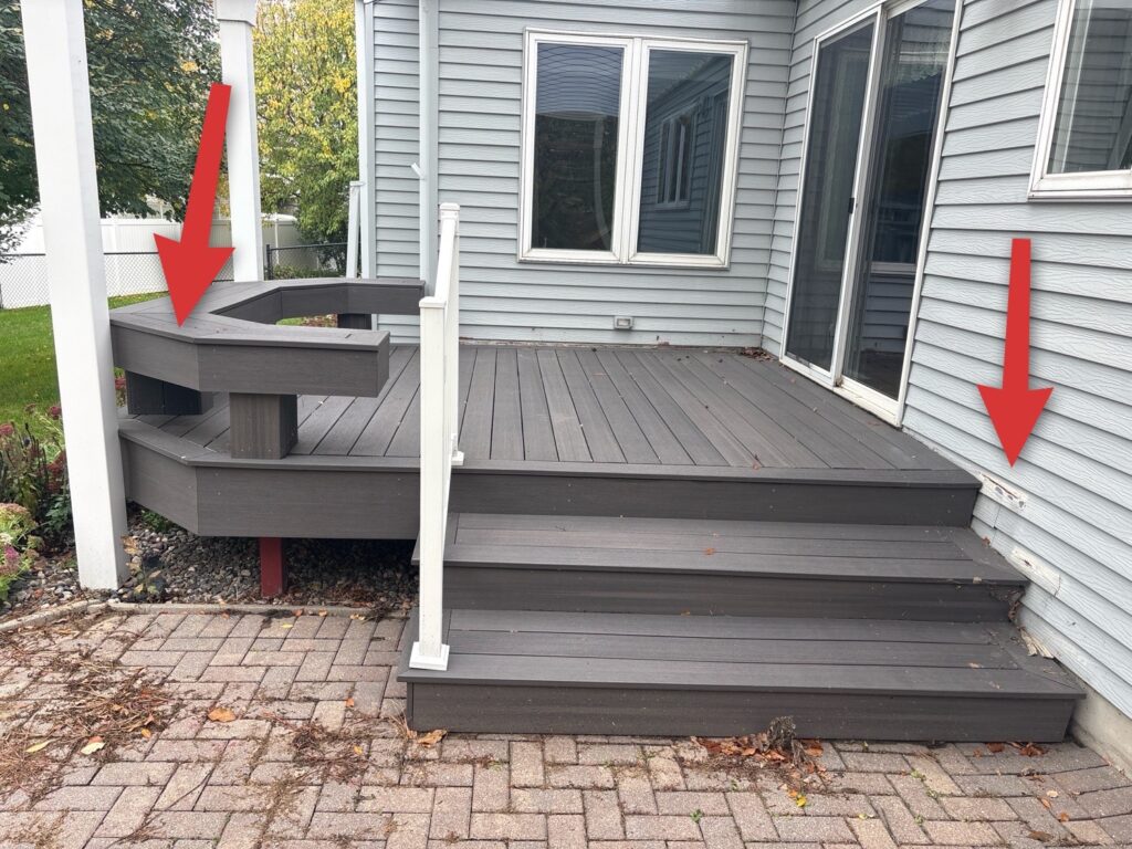 Composite deck and steps on a paver patio, with arrows pointing to corners where the deck has settled.