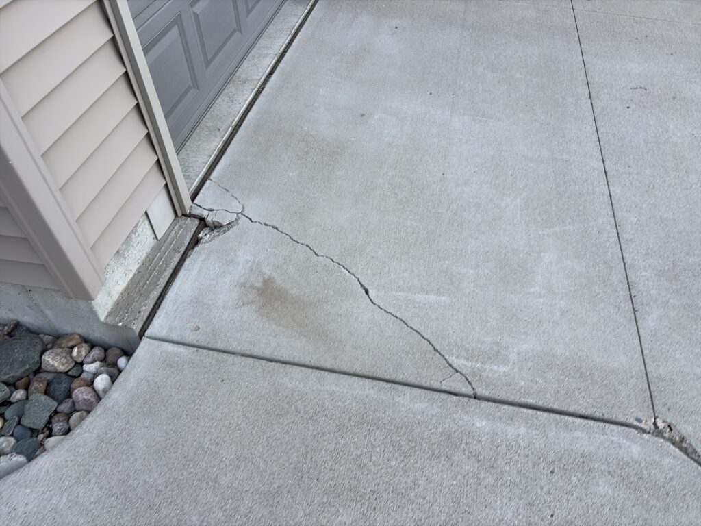 Crack running from the garage corner across a concrete driveway