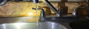 Frozen kitchen faucet with an icicle hanging from the spout in a North Dakota home