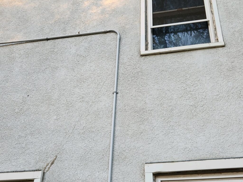 Crack in stucco running down the wall from the corner of a window