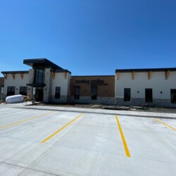 A commercial building with the sign "Saving Smiles Dentistry" in front of an empty parking lot under a clear blue sky.